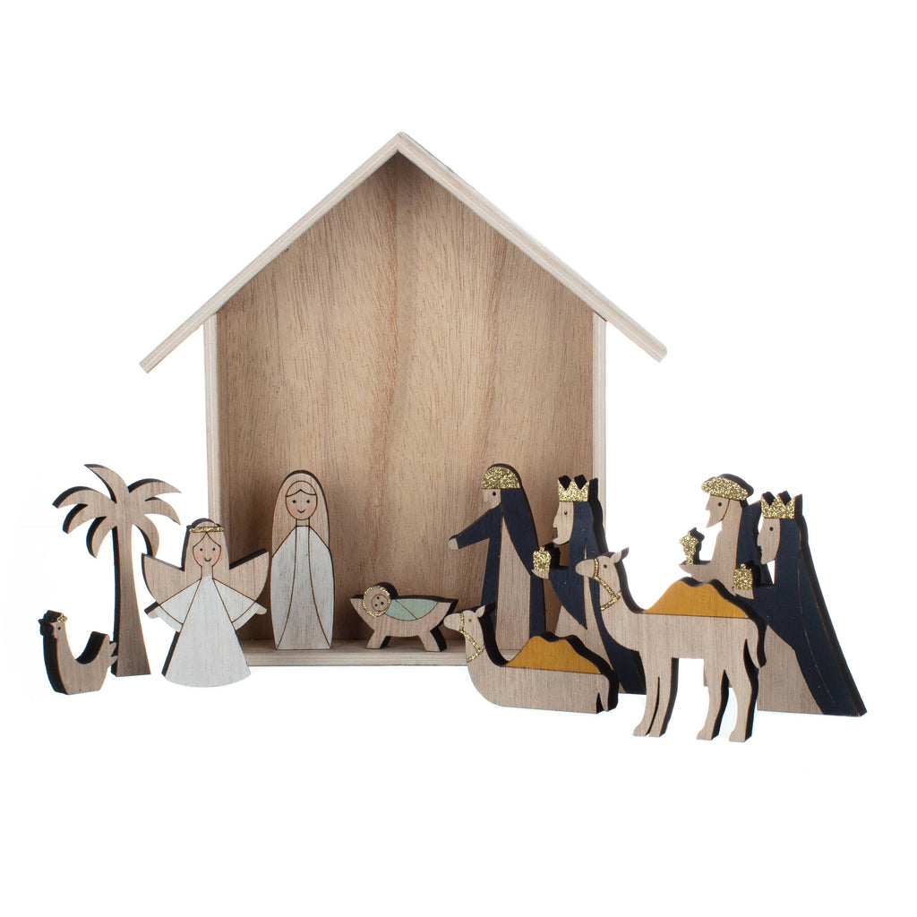 A wooden nativity scene set featuring a stable backdrop with stylized figures of the Holy Family, wise men, an angel, and a palm tree, crafted from light natural wood with dark navy accents.